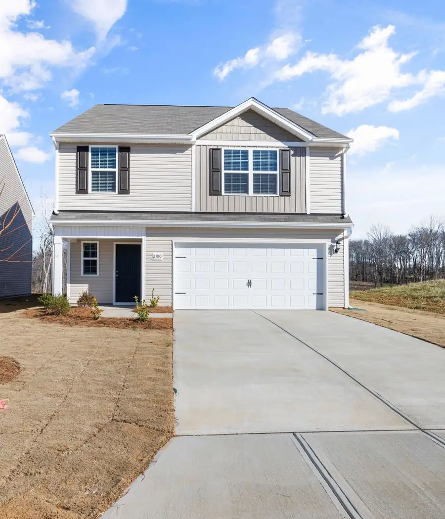 Two-story house with a white garage door and a new concrete driveway